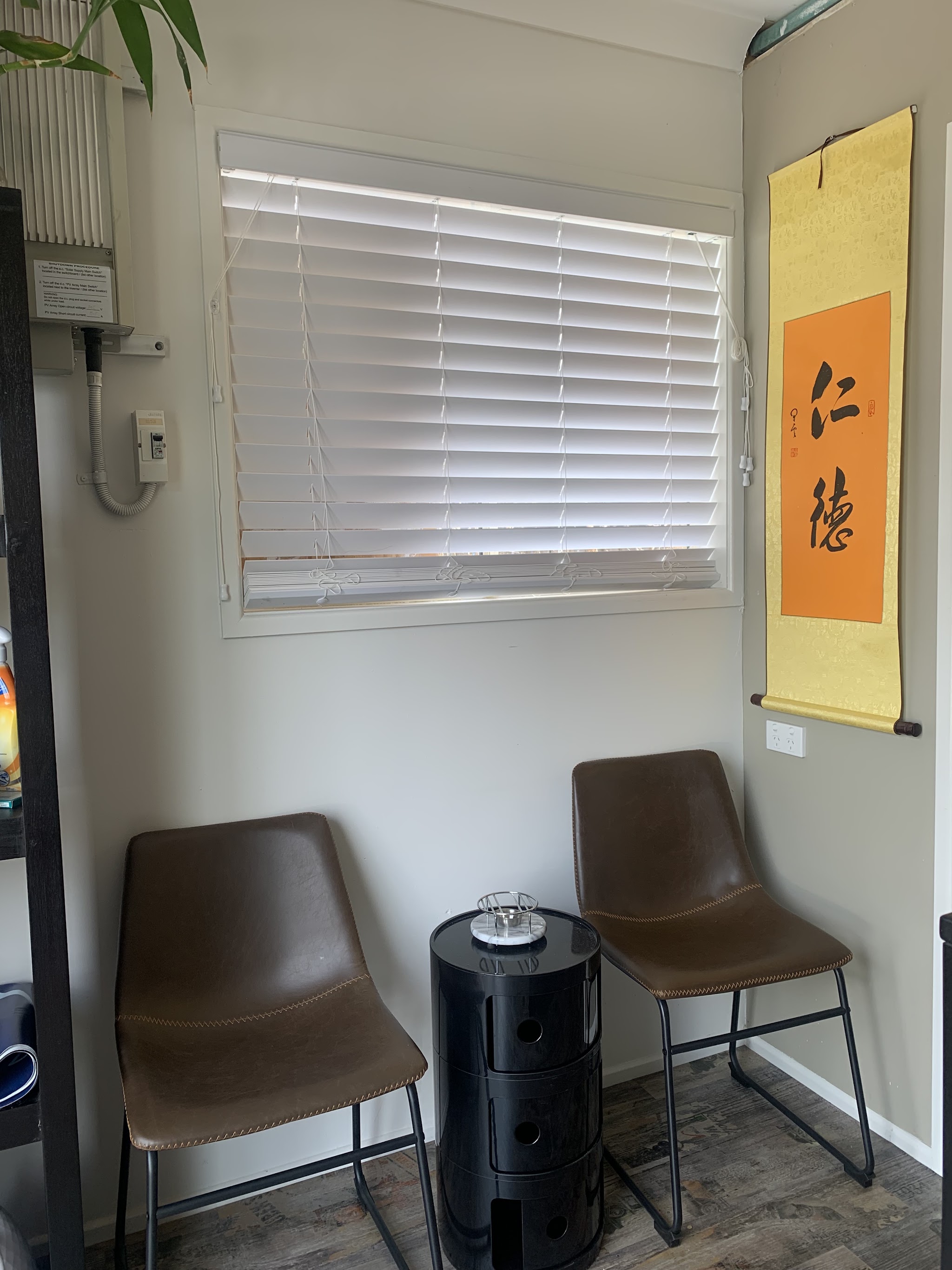 The clinic's waiting nook, two chairs beneath a Chinese calligraphy scroll