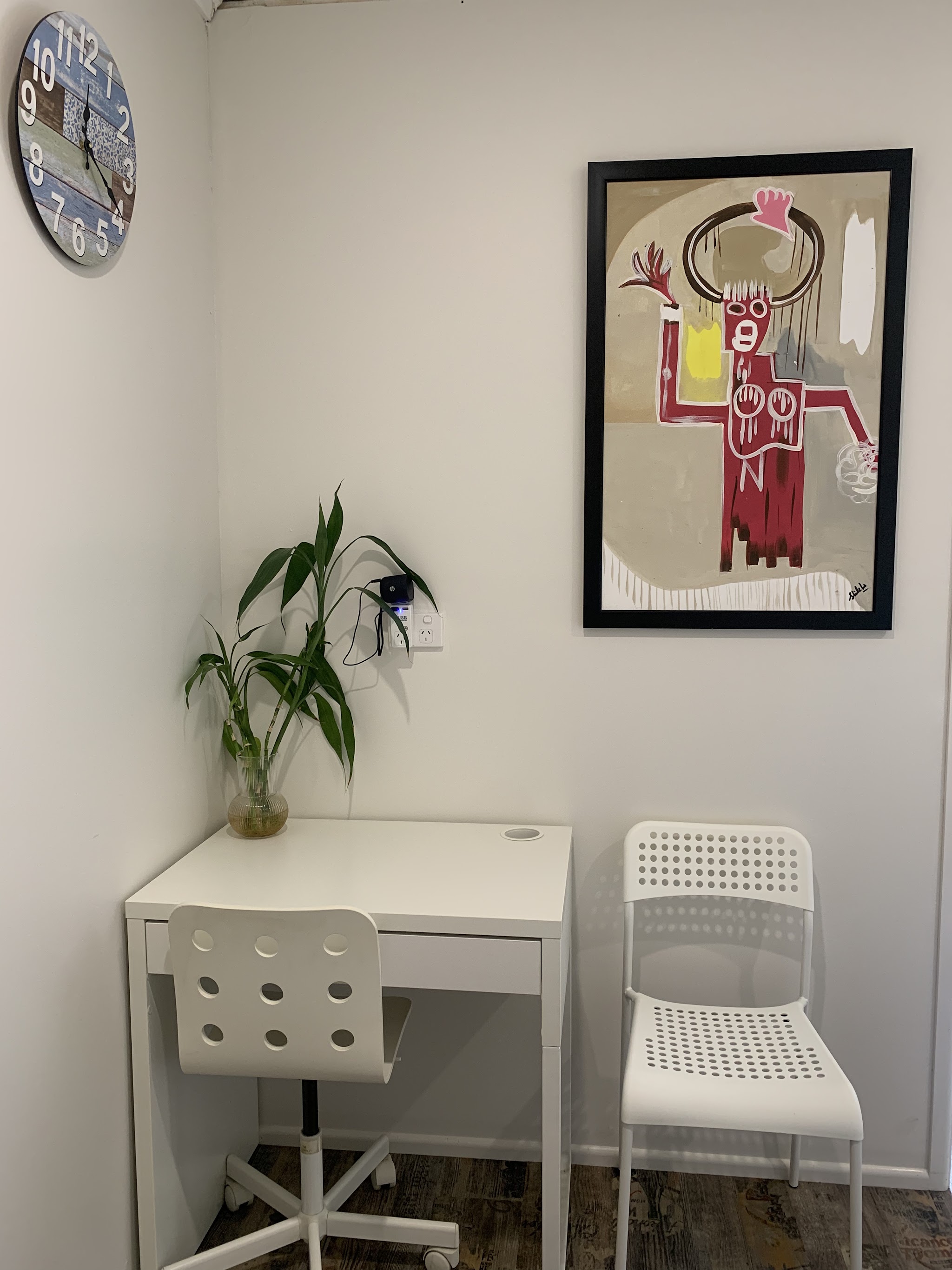 A quiet corner of the clinic with a wall clock, framed print and a plant